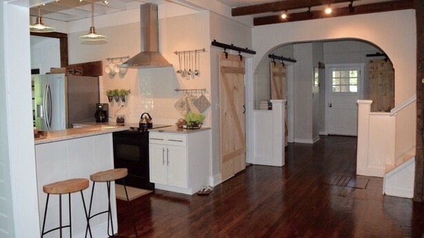 A kitchen with a central island, bar stools, and a hanging pot rack.