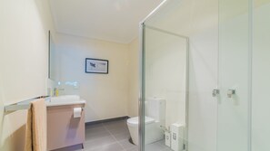 A modern bathroom with a glass shower enclosure, a white toilet, and a sink with a towel. - Unit 2-83 Thompson Avenue, Cowes, Spacious 2 bedroom Unit, includes linen. (Cowes)