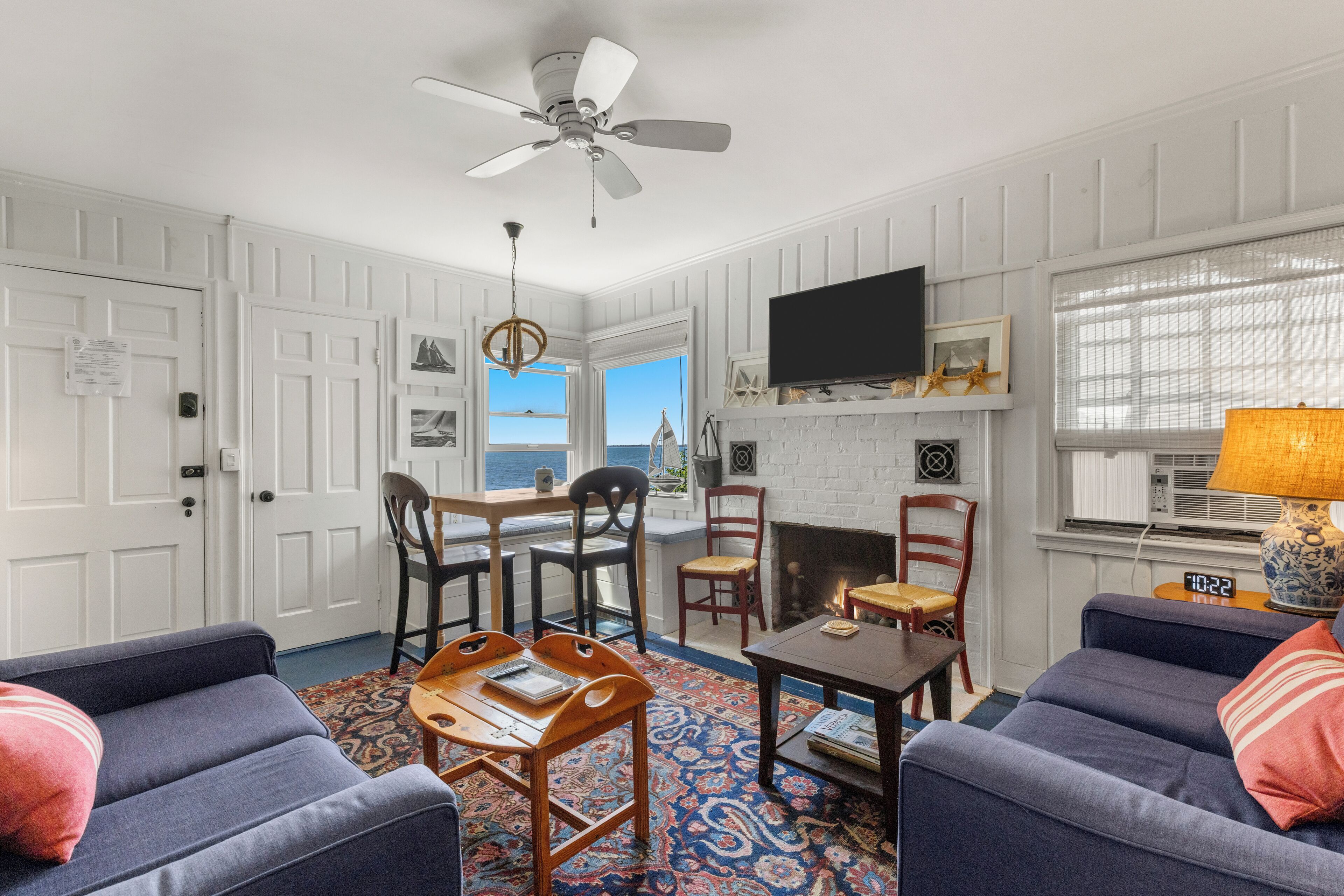 A living room with a fireplace, a ceiling fan, and a TV mounted on the wall.