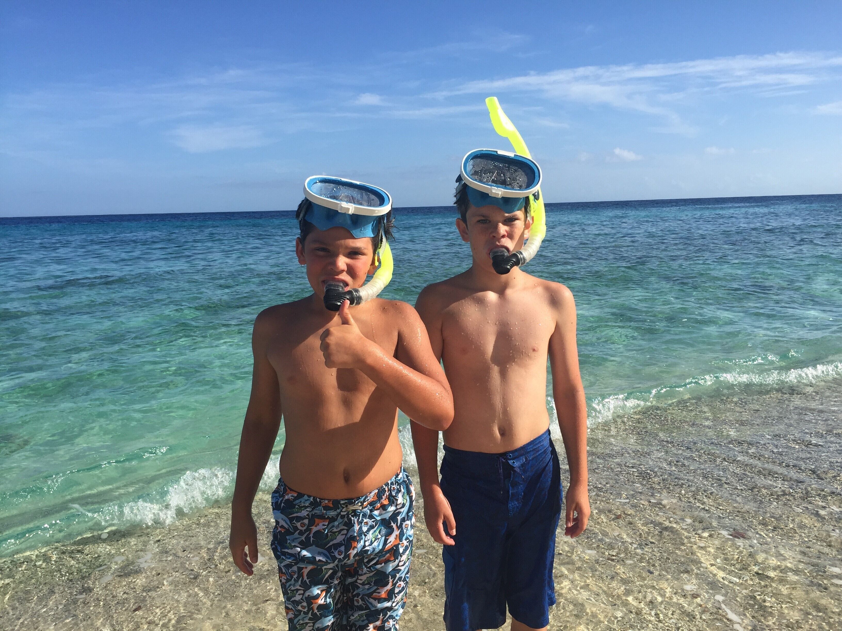 Zwei Personen an einem Strand, im Hintergrund klares Wasser und ruhige See.