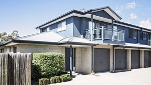 Ein zweigeschossiges Wohnhaus mit Balkon, einer Garage mit zwei Toren und einem Holzzaun.