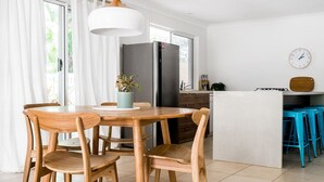 Une cuisine moderne avec un îlot central, des chaises en bois, une plante en pot et une horloge au mur.