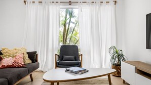 Un salon avec un canapé, un fauteuil, une table basse et un téléviseur fixé au mur.