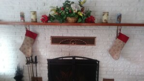 A fireplace with two stockings, a wooden mantel, and a brick wall.