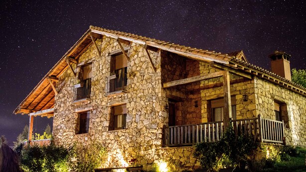 Un edificio de piedra con un balcón, bajo un cielo estrellado.