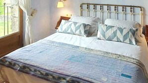 Un dormitorio con cama, un cuadro de noche estrellada, una ventana con cortinas y techo de madera.