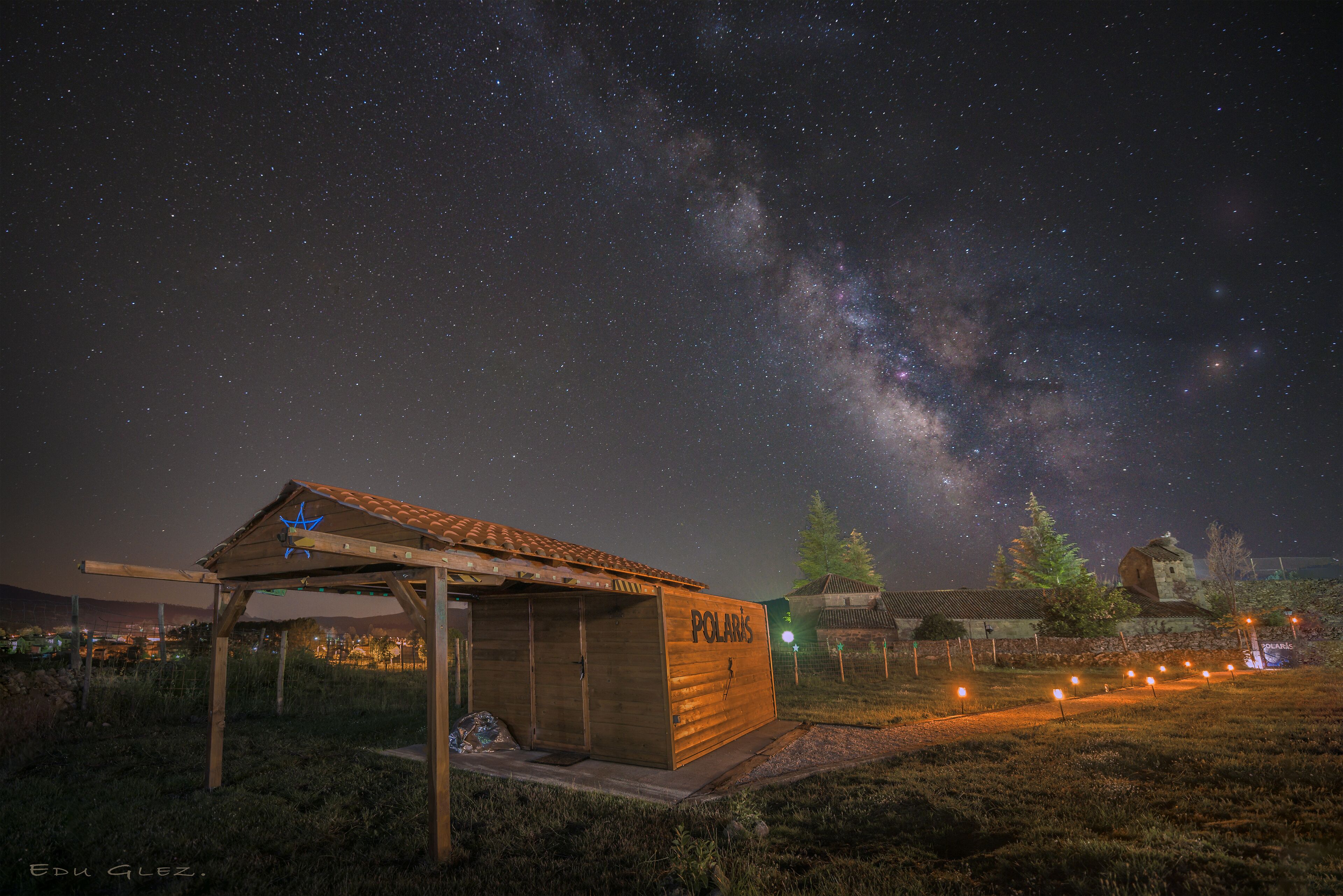 A wooden structure labeled "POLARIS" with a star-shaped roof, set against a night sky with visible stars and the Milky Way.
