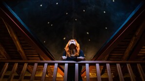 Una persona parada en un balcón con un techo estrellado.