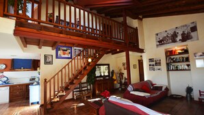 Amplia sala de estar con una escalera de madera, un comedor y una zona de estar acogedora.