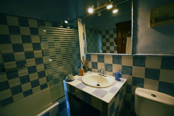 Ein Badezimmer mit Schachbrettfliesen, einem Waschbecken, einem Spiegel und einer Toilette.