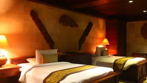 Habitación de hotel con dos camas, cabeceros de madera, un reloj en la pared y dos lámparas de noche.