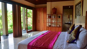 Un dormitorio amplio con una cama grande, un armario de madera y vistas a la vegetación.