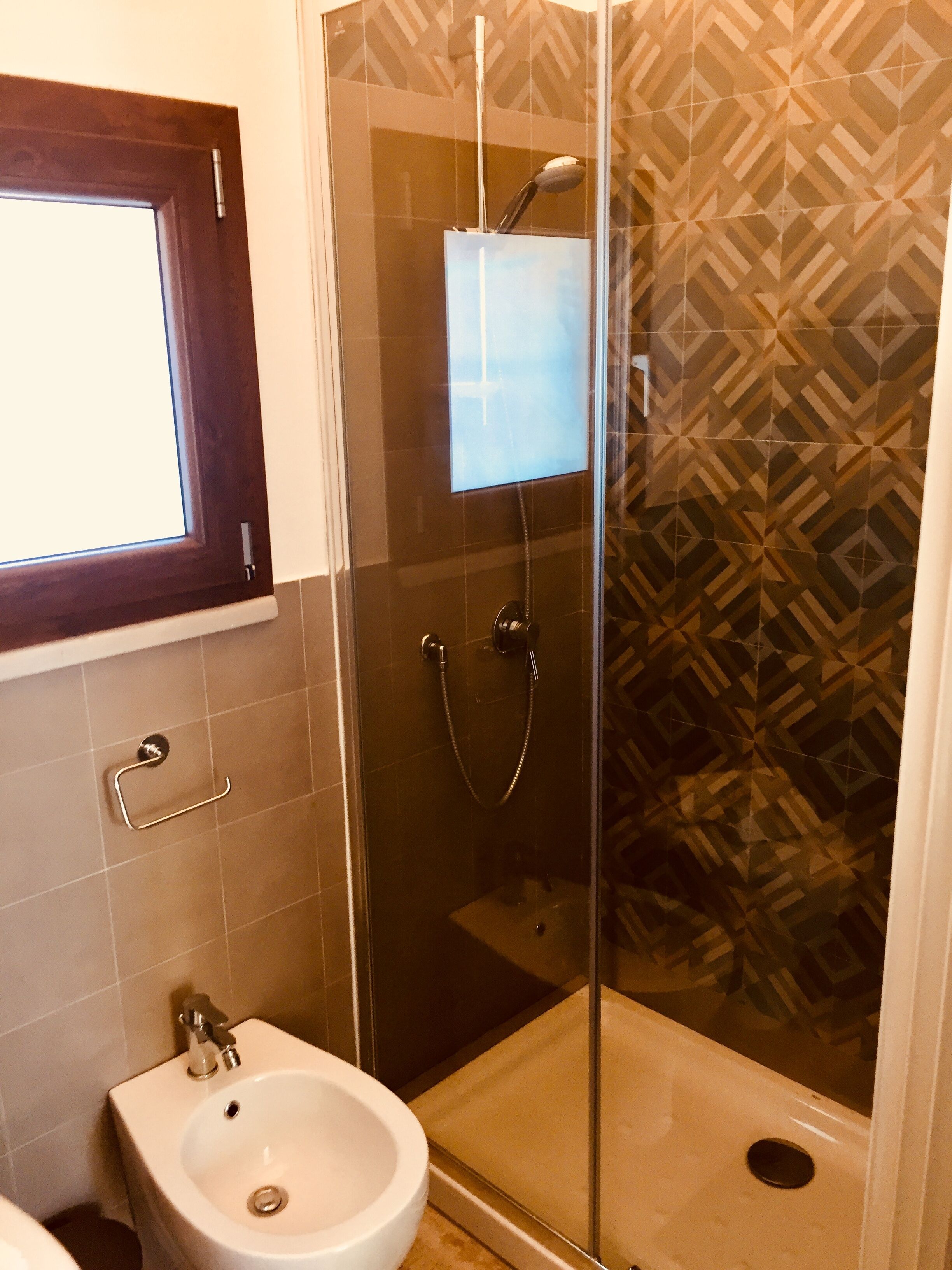 A bathroom with a glass shower enclosure, a sink, and a toilet.