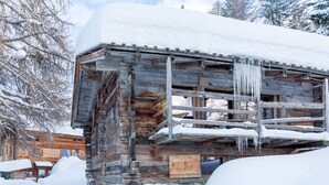 Eine rustikale Holzhütte mit Steinunterbau, umgeben von Schnee.