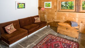 Ein gemütliches Zimmer mit einem braunen Sofa, einer Holzablage und einem roten Teppich mit Muster.