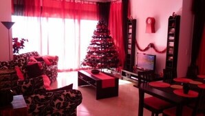 A living room with a Christmas tree, red curtains, and a TV.