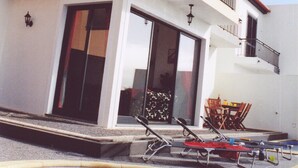 A two-story building with a swimming pool, a balcony, and outdoor furniture.