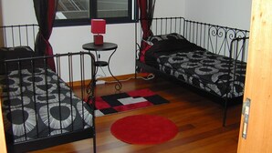 A room with two beds, a small table, and a window with curtains.