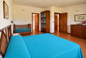 A bedroom with a large bed, a wooden crib, a dresser, and a wardrobe. -  Beachfront Villa with spacious garden and direct beach access  (San Sostene Marina)