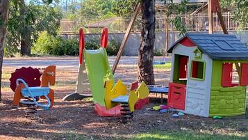 A playground with swings, a slide, and a small playhouse.