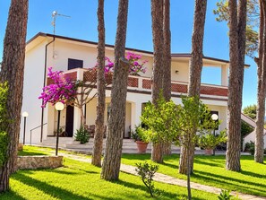 A two-story building with a balcony, surrounded by trees and a well-maintained lawn. -  Beachfront Villa with spacious garden and direct beach access  (San Sostene Marina)