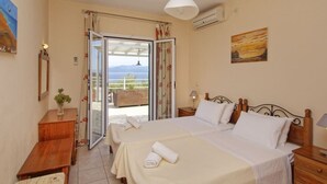 Ett hotellrum med två sängar, en balkong med utsikt, en tavla på väggen och en luftkonditioneringsanläggning.