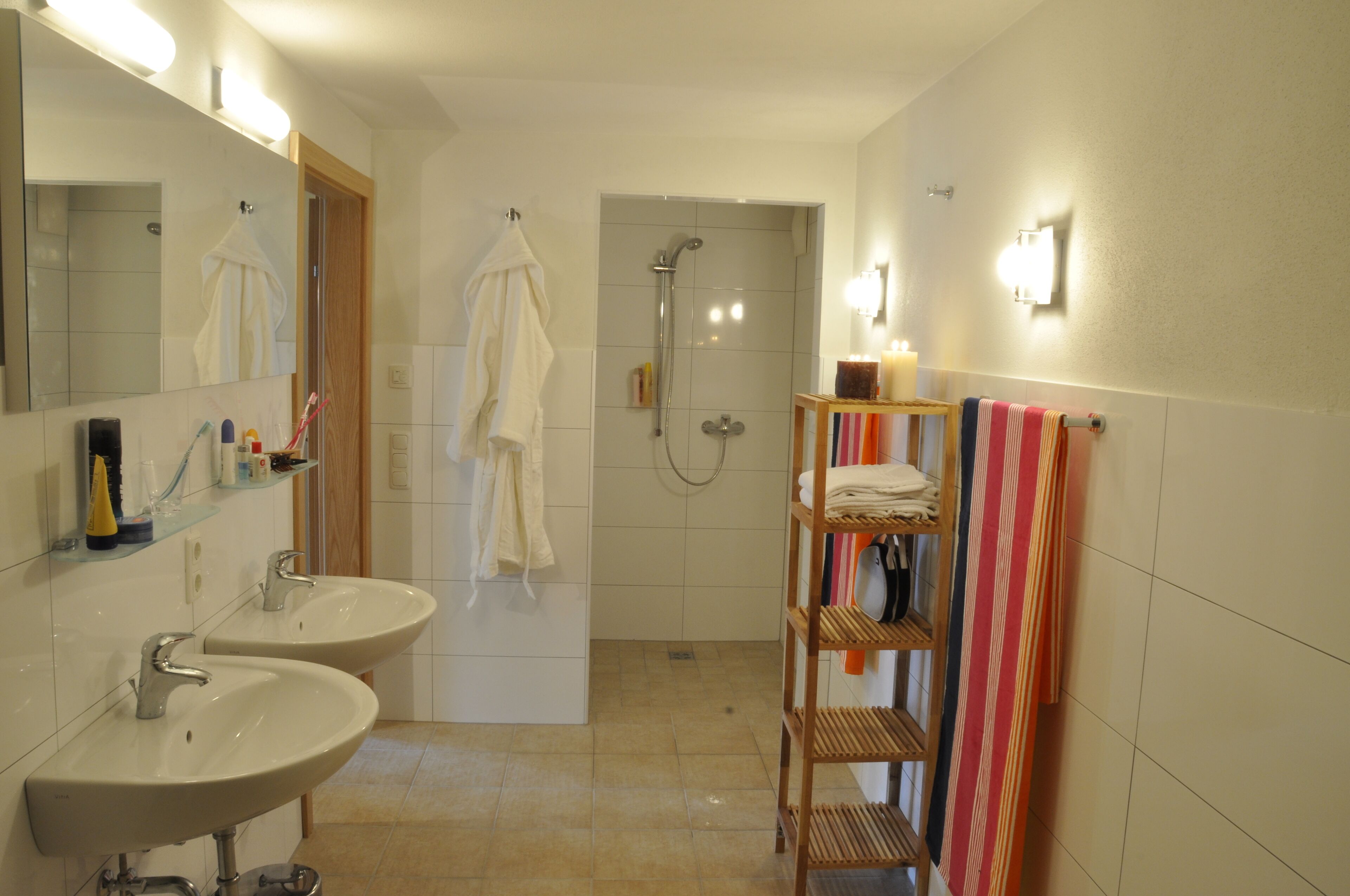 Ein Badezimmer mit zwei Waschbecken, einer Dusche und einem Handtuchhalter mit mehreren Handtüchern.