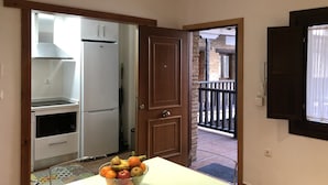 Una cocina con un refrigerador blanco, una puerta de madera y un frutero sobre la encimera.
