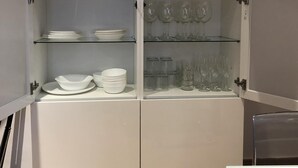 Un mueble blanco con varios estantes, algunos con platos y vasos.