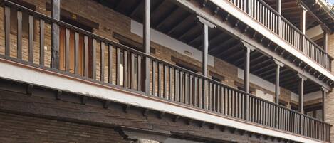 A multi-story building with a balcony, stone columns, and a tiled ground floor.