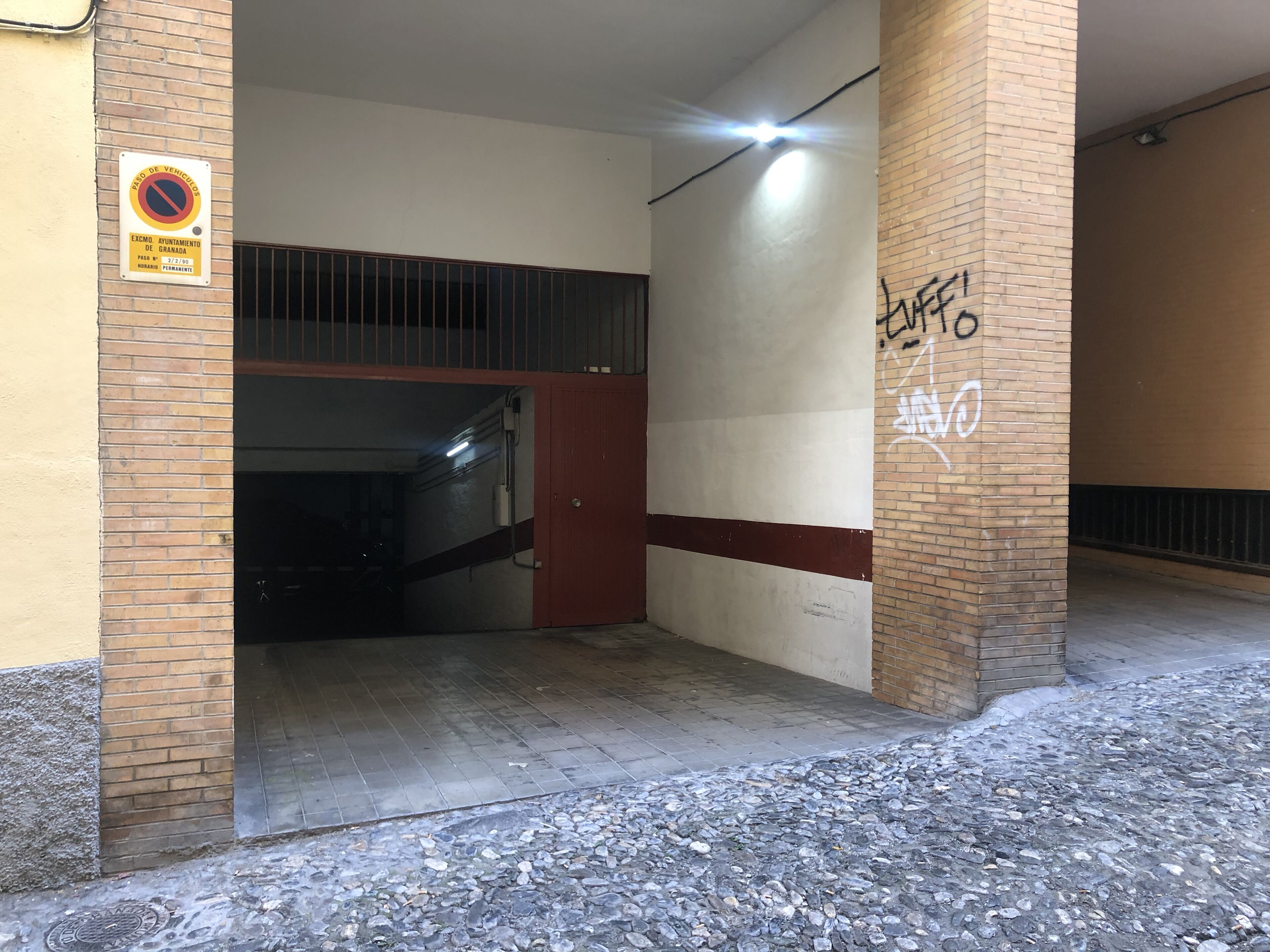 An entrance to a building with a no parking sign, a staircase, and graffiti on the wall.