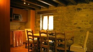Un comedor acogedor con pared de piedra, sillas de madera y una mesa.