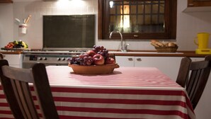 Une cuisine équipée d’une cuisinière, d’un évier et d’un saladier rempli de fruits posé sur une table.