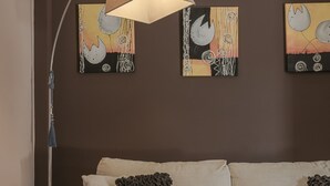 Ett modernt vardagsrum med en soffa, dekorativa kuddar, en golvlampa och konst på väggen.