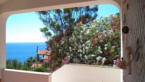 A balcony with a view of the sea and a building with a tiled roof. - Apartment surrounded by tranquility with beautiful sea view (Capoliveri)