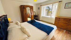 Ein Schlafzimmer mit einem großen Bett, einer hölzernen Kommode und einem Fenster mit Vorhängen.