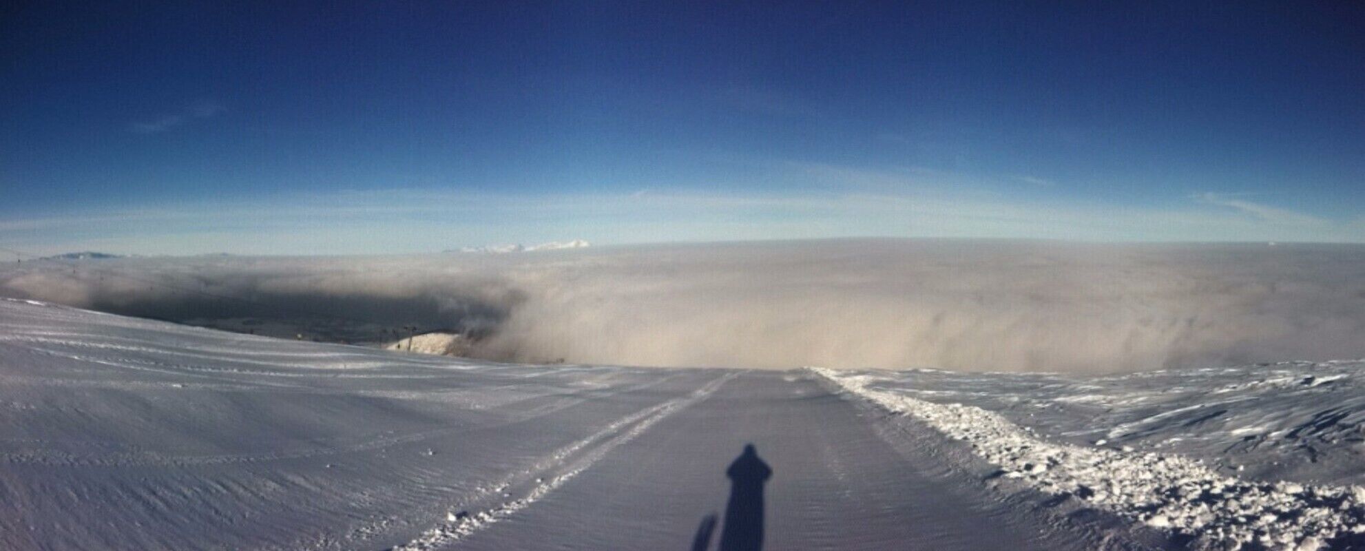 Una strada innevata con l'ombra di una persona che cammina.