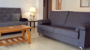 A living room with a grey sofa, a wooden coffee table, and a lamp on a side table. - Front Line 4th floor La Goleta Apt Overlooking Benidorm Island And Levante Beach (Benidorm)