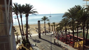 A beachside street with palm trees, a pedestrian crossing, and a view of the beach and ocean. - Front Line 4th floor La Goleta Apt Overlooking Benidorm Island And Levante Beach (Benidorm)