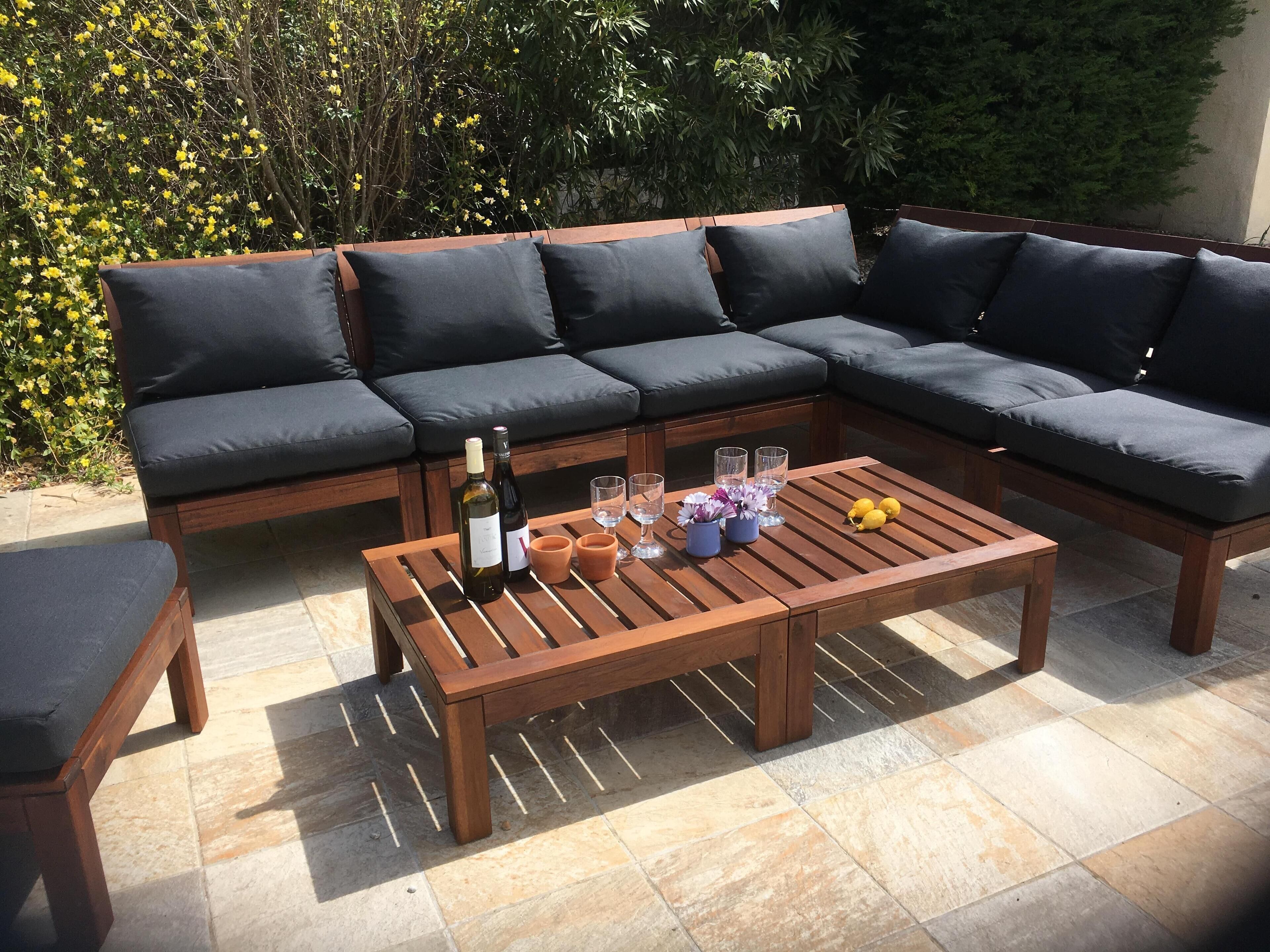 An outdoor seating area with a wooden table, a bottle of wine, and glasses.