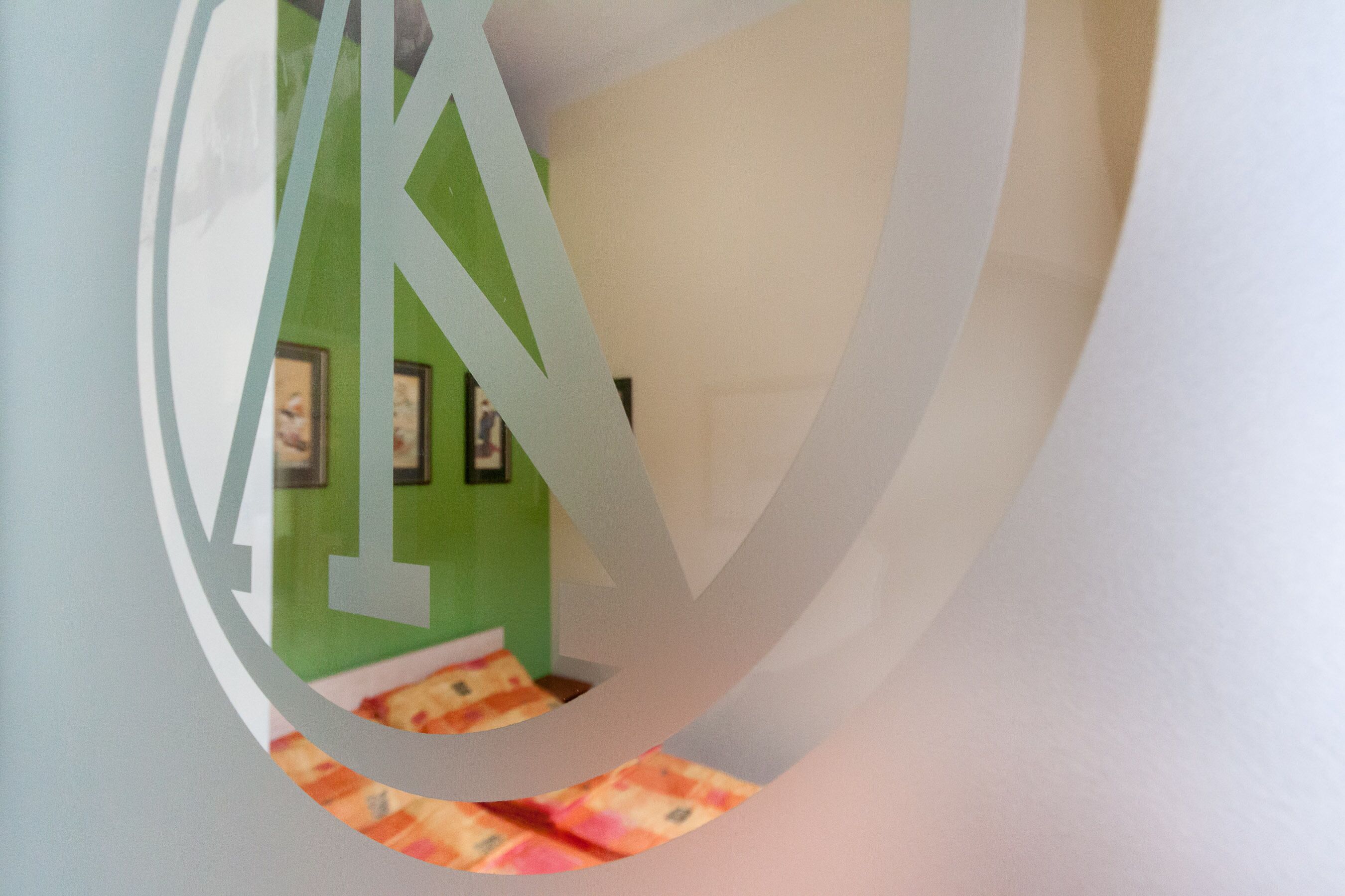 Un recorte circular con una pared verde y fotografías en el fondo.