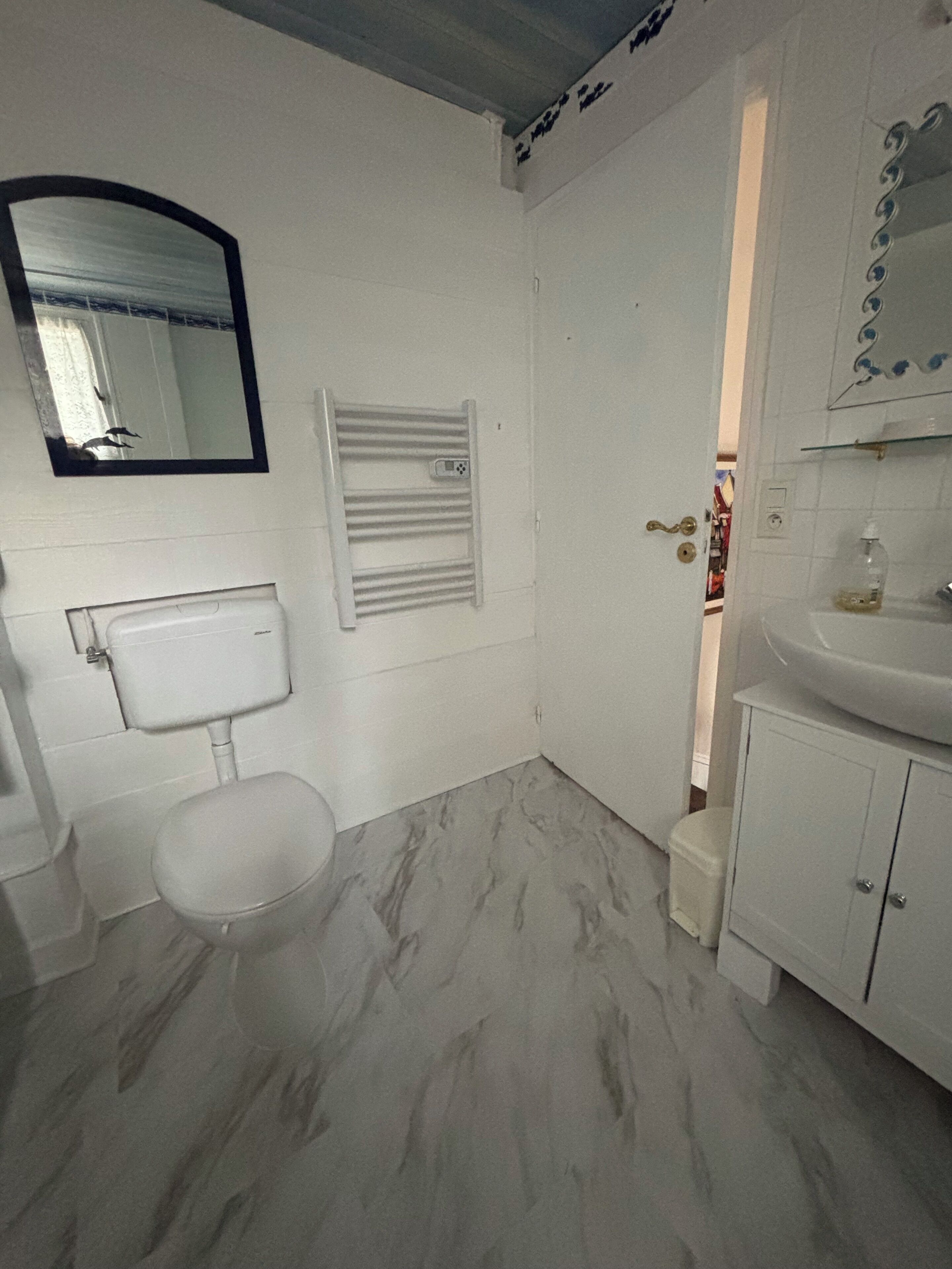 A bathroom with a toilet, a sink, a mirror, and a shower area.
