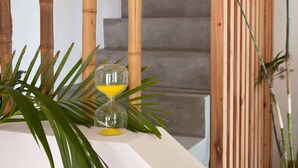 Una escalera de diseño moderno, con barandilla de madera y un vaso de zumo de naranja sobre un repisa blanca.