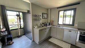 A modern kitchen with a dishwasher, sink, and a window with a view of greenery. - House for 4/5 people, beaches and shops 400 m away (Arradon)