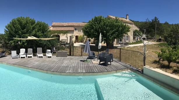 Ein Poolbereich mit Liegestühlen, Sonnenschirmen und einem Gebäude aus Stein im Hintergrund.