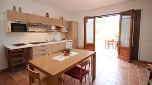 Une cuisine compacte comprenant un coin repas, un four à micro-ondes, une cuisinière et un évier.