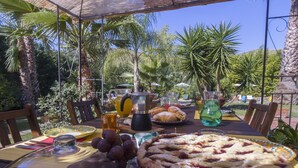 Une table dressée à l’extérieur, avec une grande tarte, une carafe de jus de fruits et une assiette de pâtisseries.