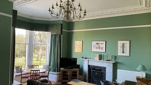 Un salón con chimenea, paredes verdes y una televisión.