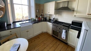 Una cocina con armarios blancos, una estufa y un lavabo.