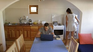 Cozinha acolhedora com armários de madeira, fogão e mesa de jantar com um laptop.